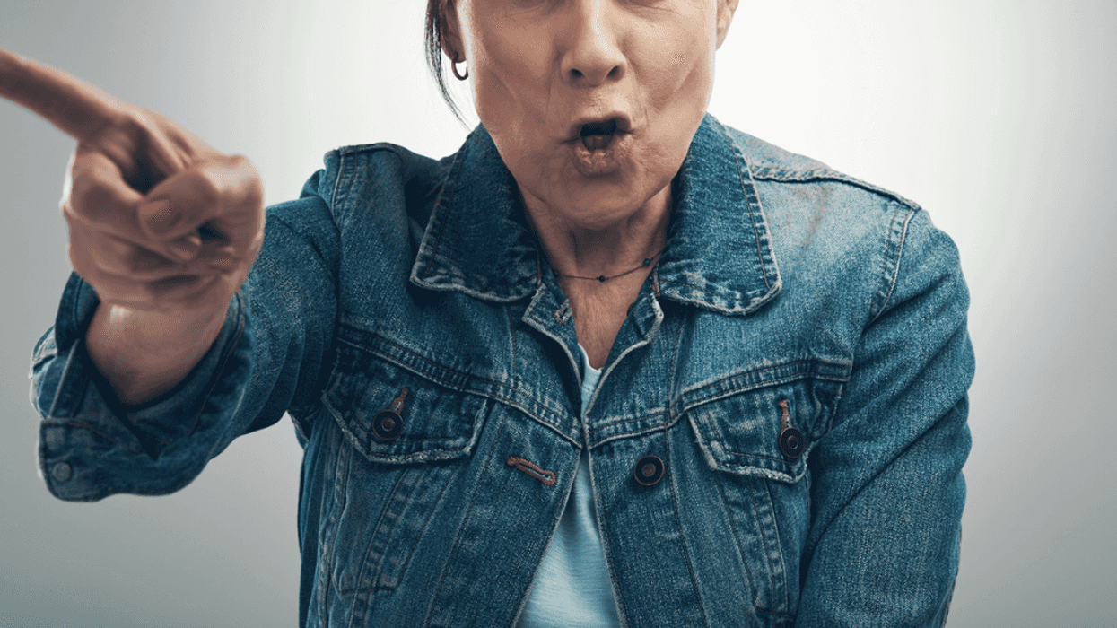 A an older woman scowling and pointing a finger.