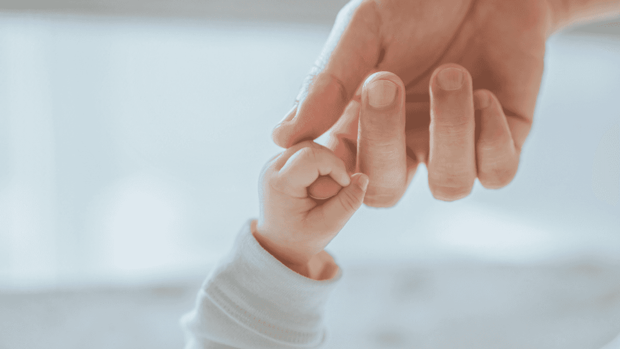 A baby holding a grown ups hand