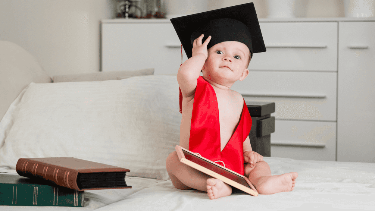 A baby wearing a graduation cap and sash.
