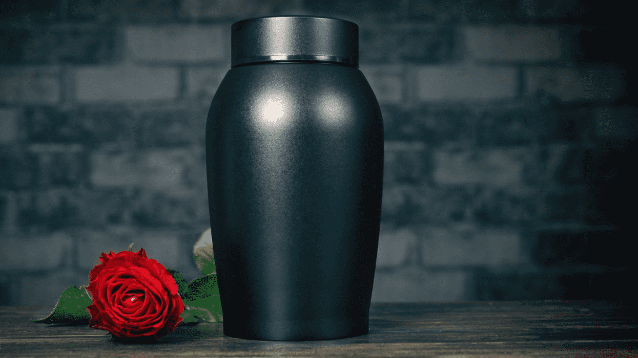 A black urn with a rose laying down next to it.