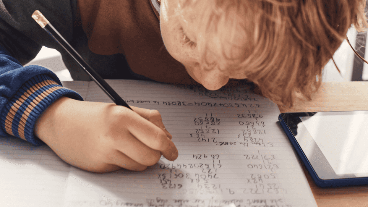 A boy doing math on a notepad.