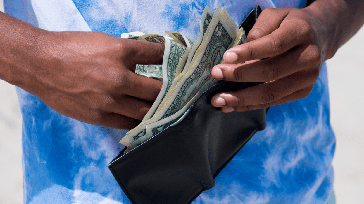 A boy taking money out of a wallet.