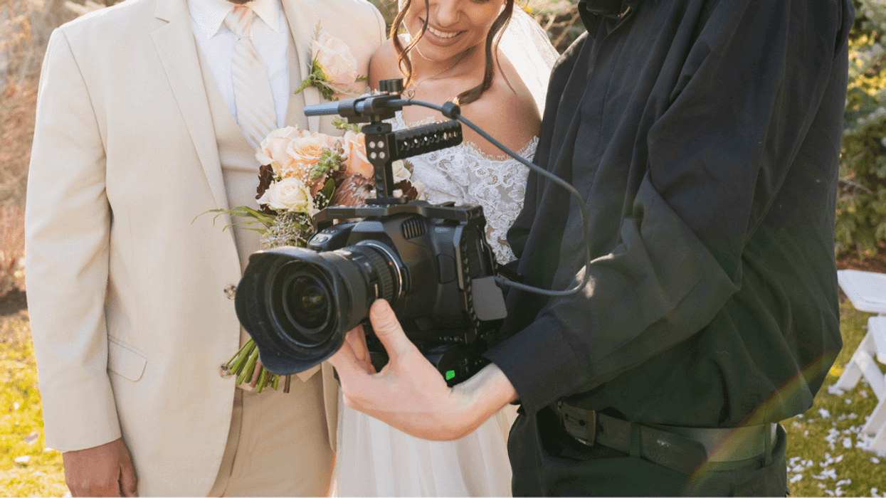A bride and groom looking at pictures on a digital camera.