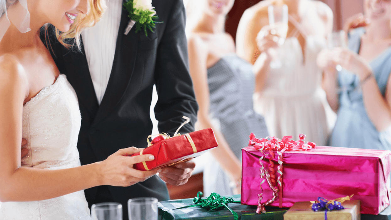 A bride and groom opening presents as bridesmaids look on