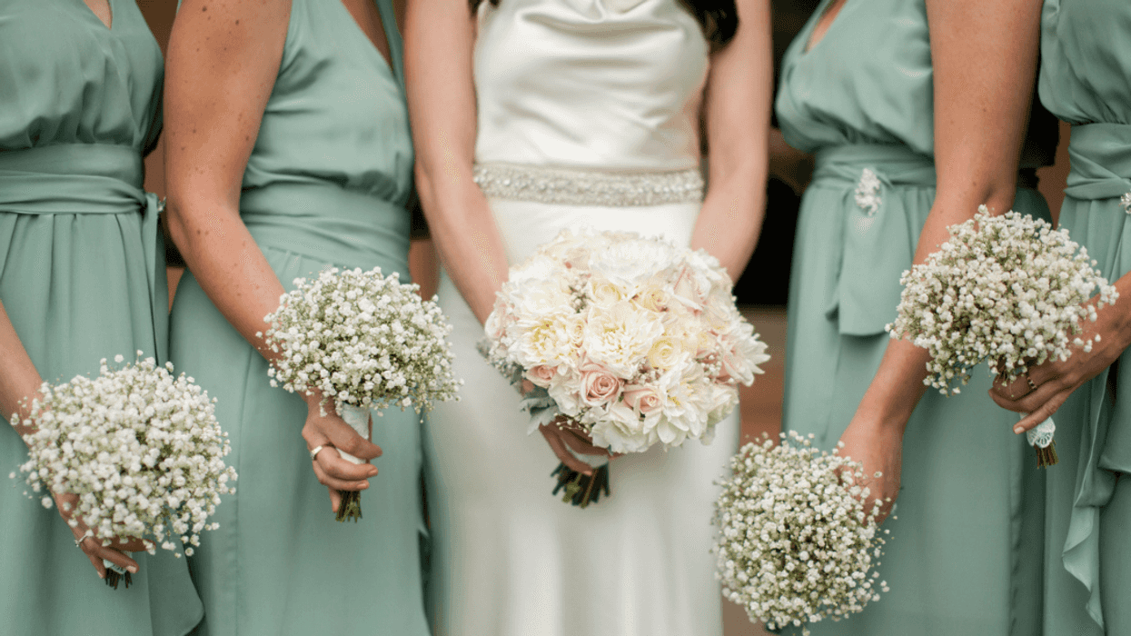 A bride holding a bouquet surrounded by bridesmaids in green dresses.