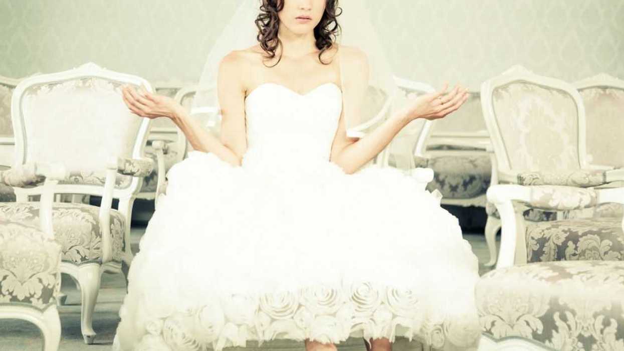 A bride sits with her arms out weighing options