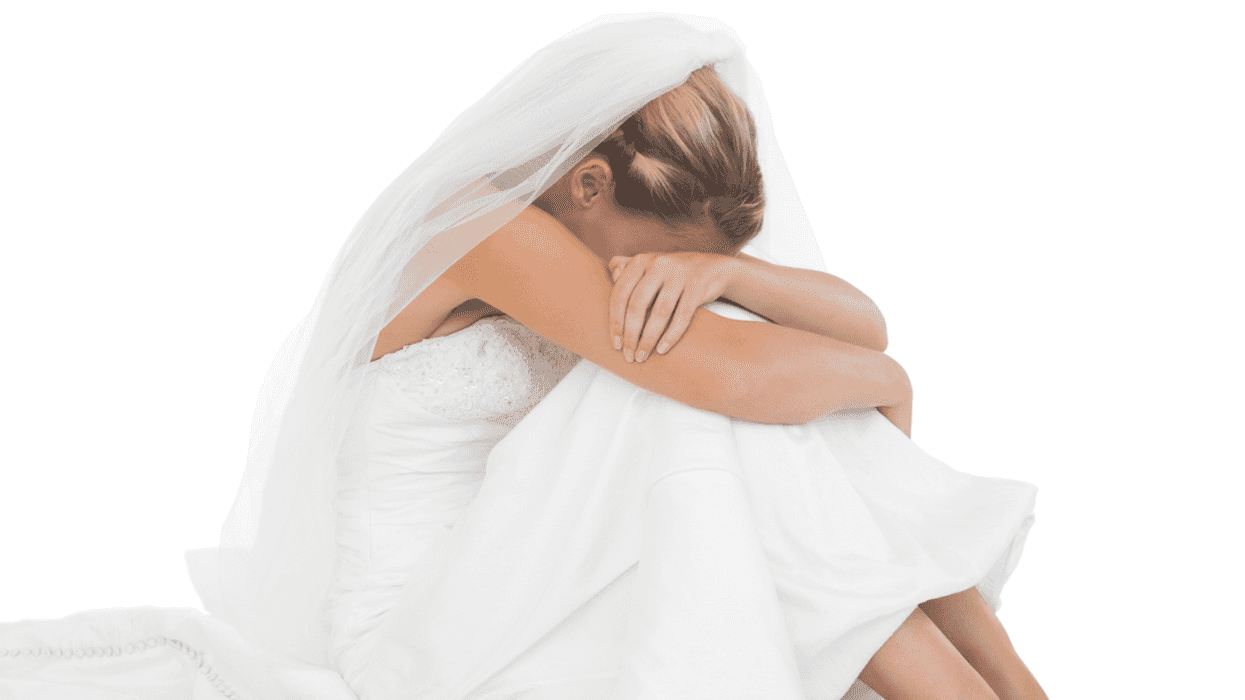 A bride sitting down with resting her head between her knees.