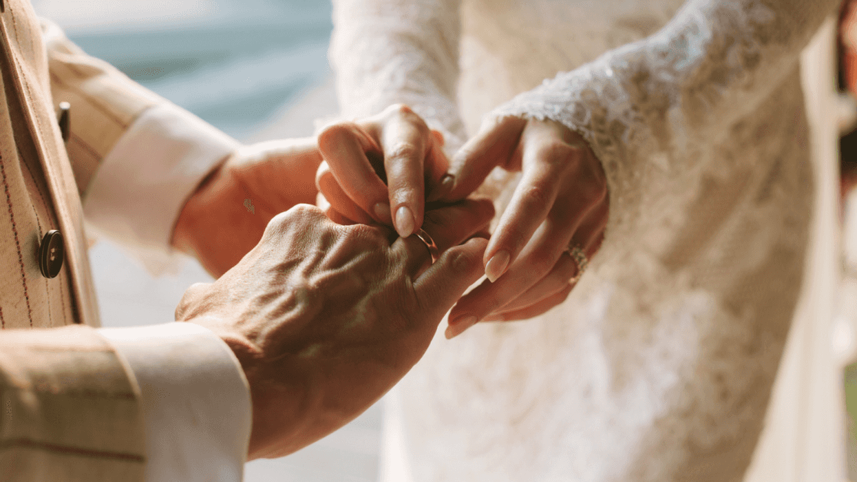 A bride slipping a ring on her groom's finger.
