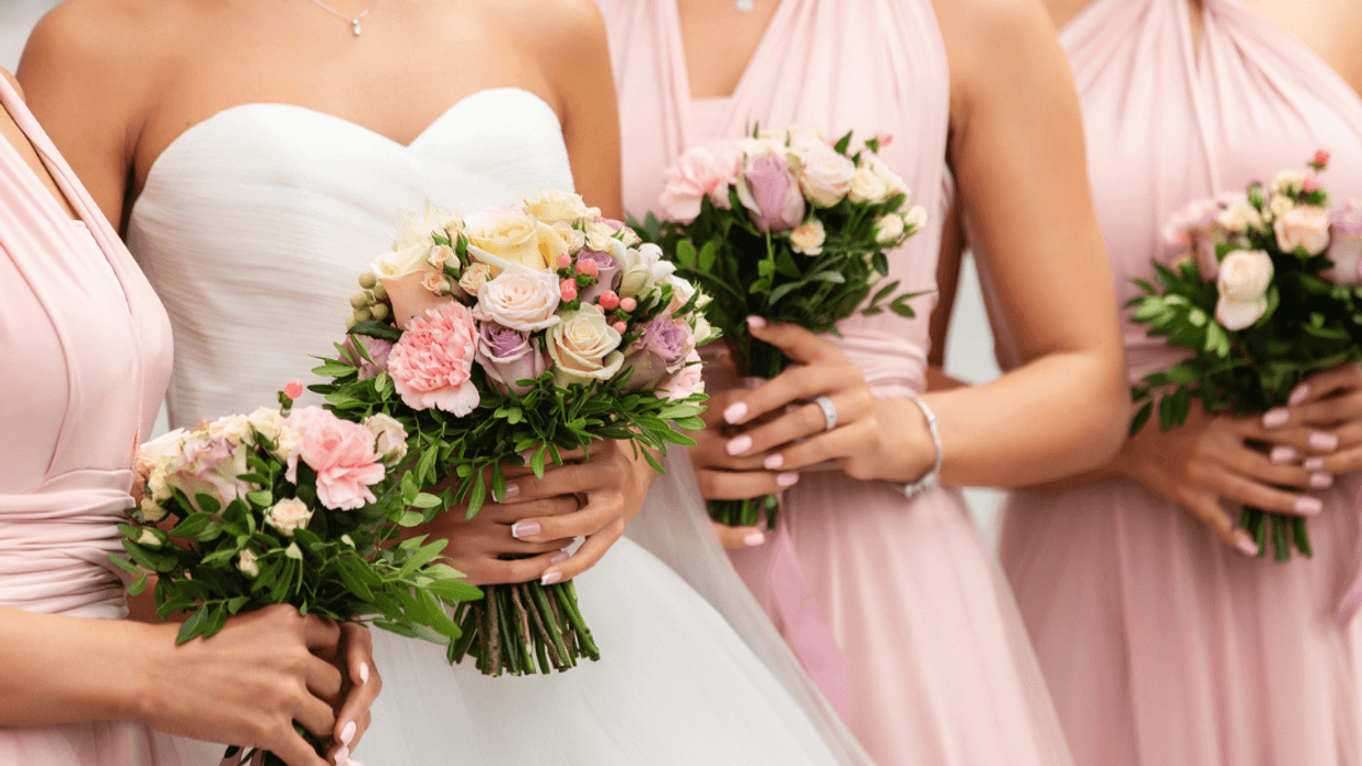 A bride surrounded by bridesmaids in pink bridesmaids dresses.