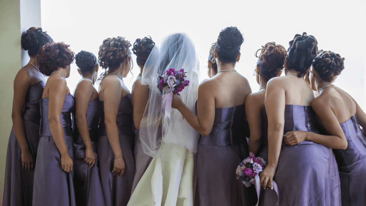 A bride surrounded by Bridesmaids in purple dresses.