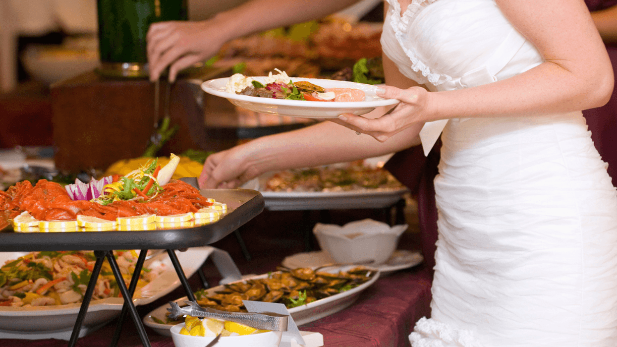 A bride taking food from a buffet.