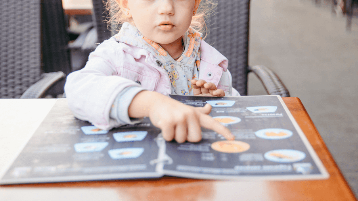A Child sitting at a table looking at a menu.