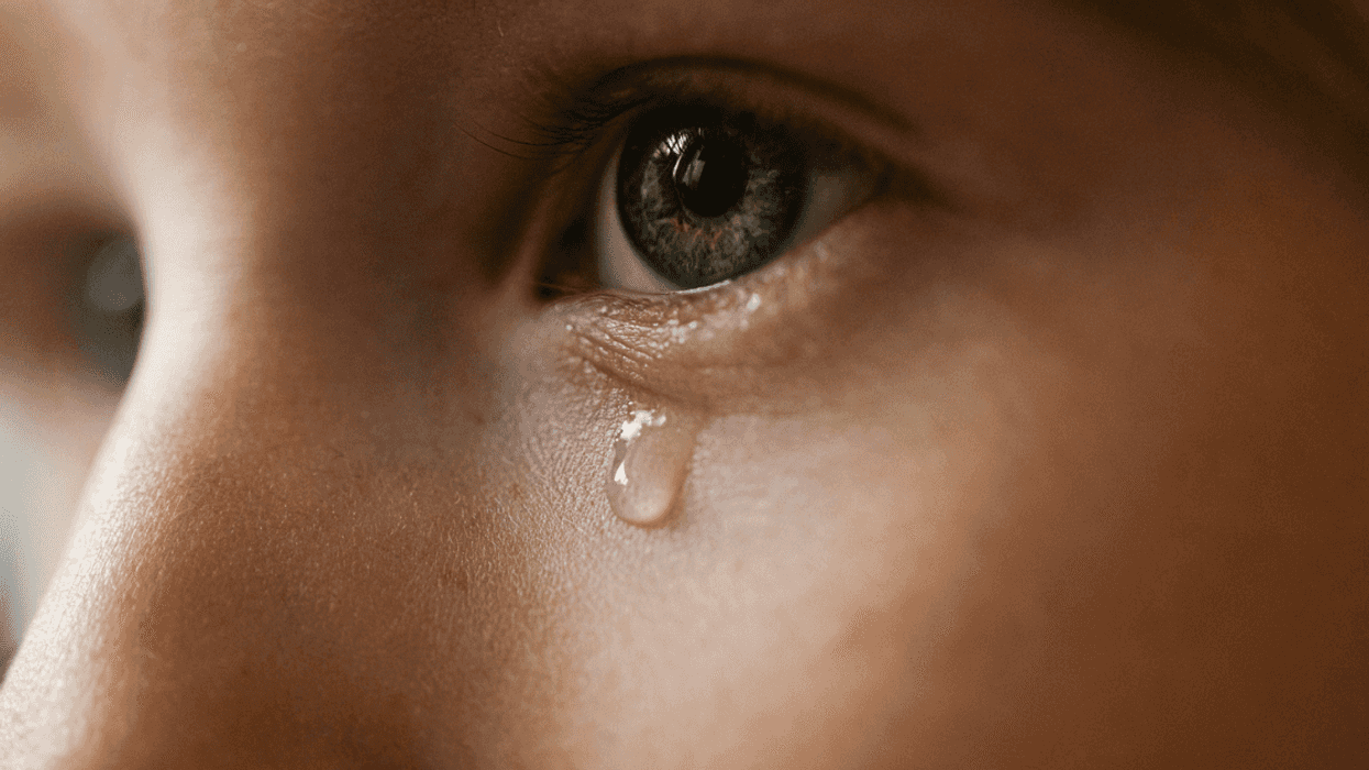 A child with a single tear falling dow their face.