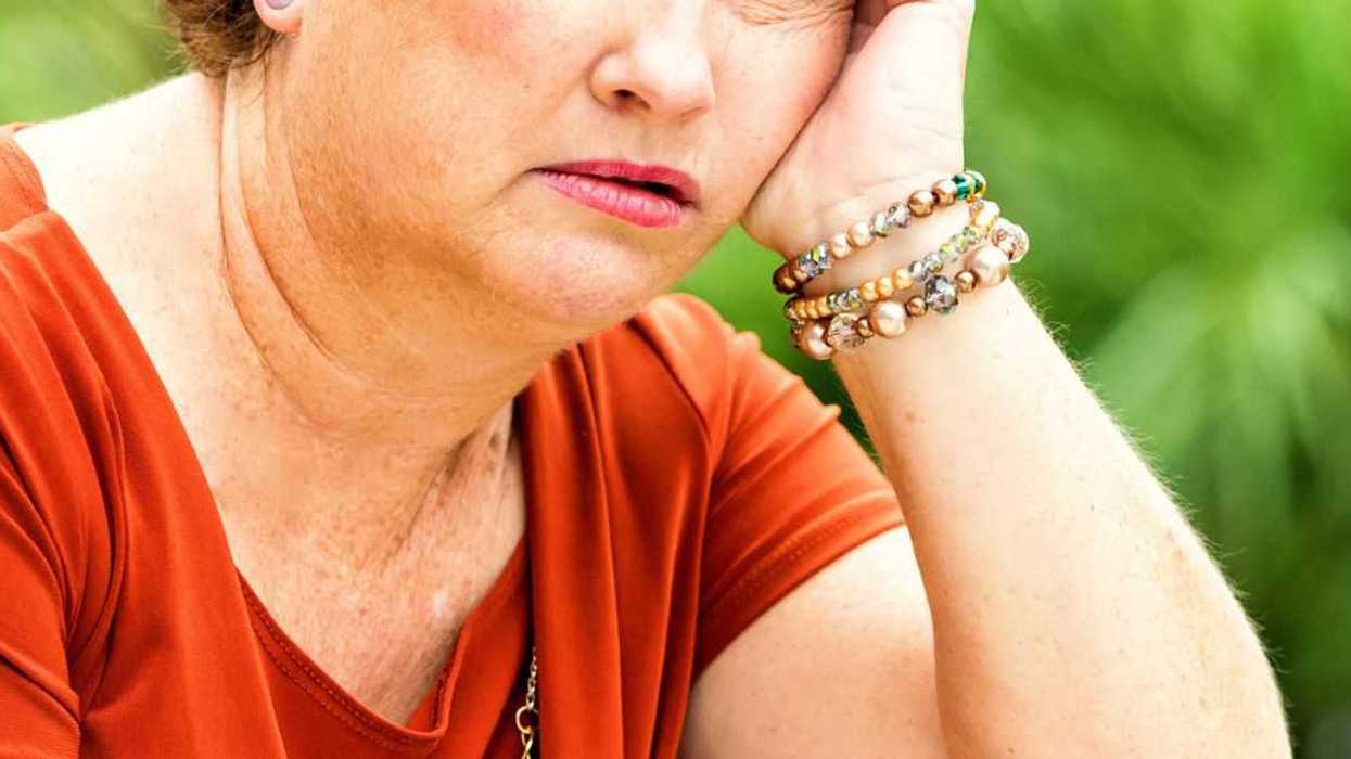 A concerned, serious, mature redhead woman stares off in space.