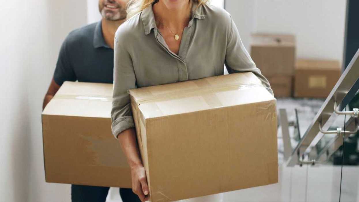A couple carrying boxes upstairs while relocating to their new home.