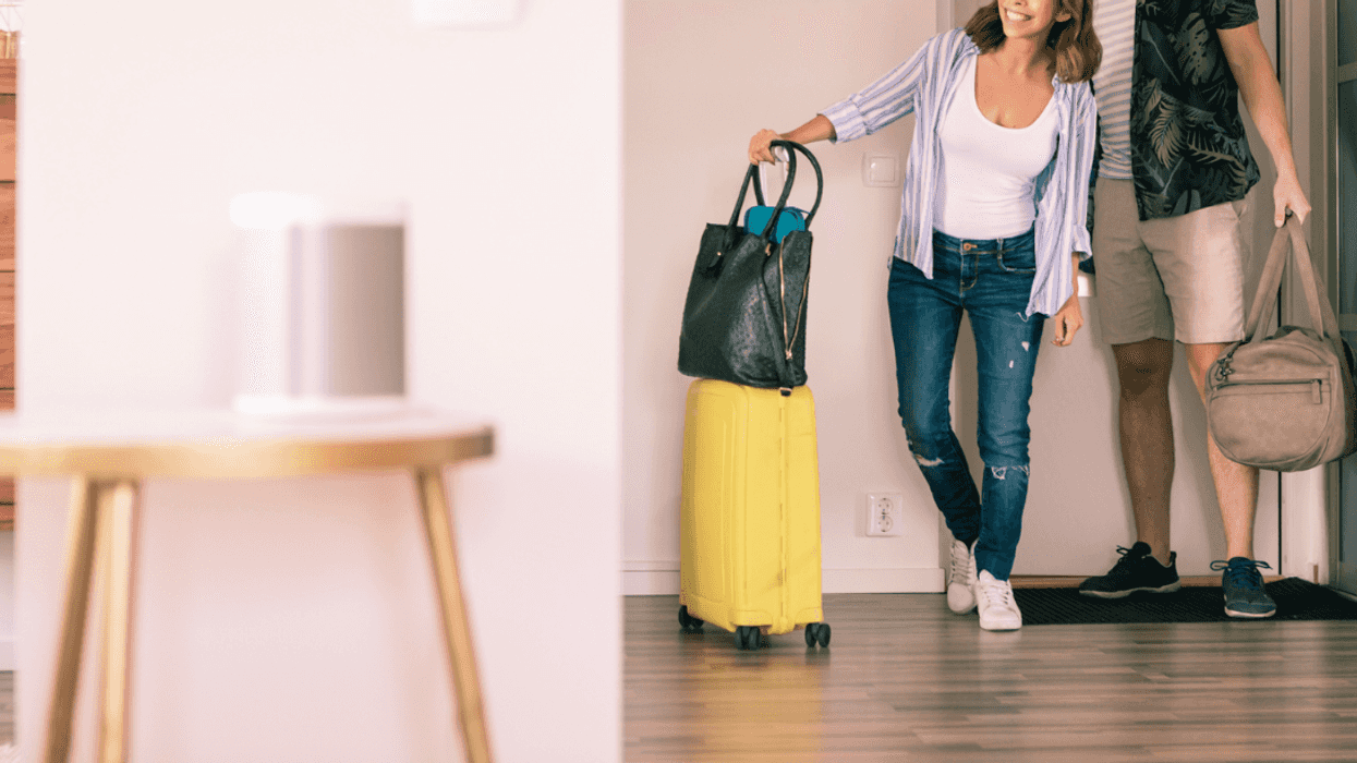 A couple entering a living room with luggage.