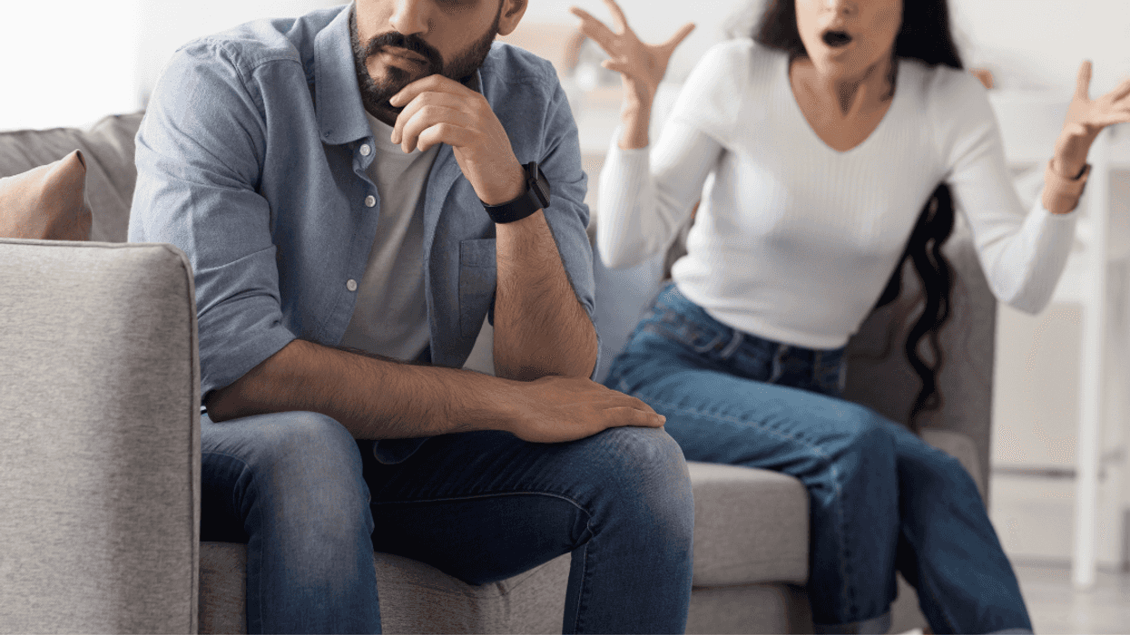 a couple seated on a couch arguing