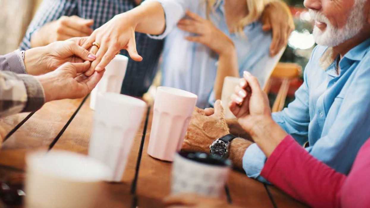 A couple shows off an engagement ring at a party