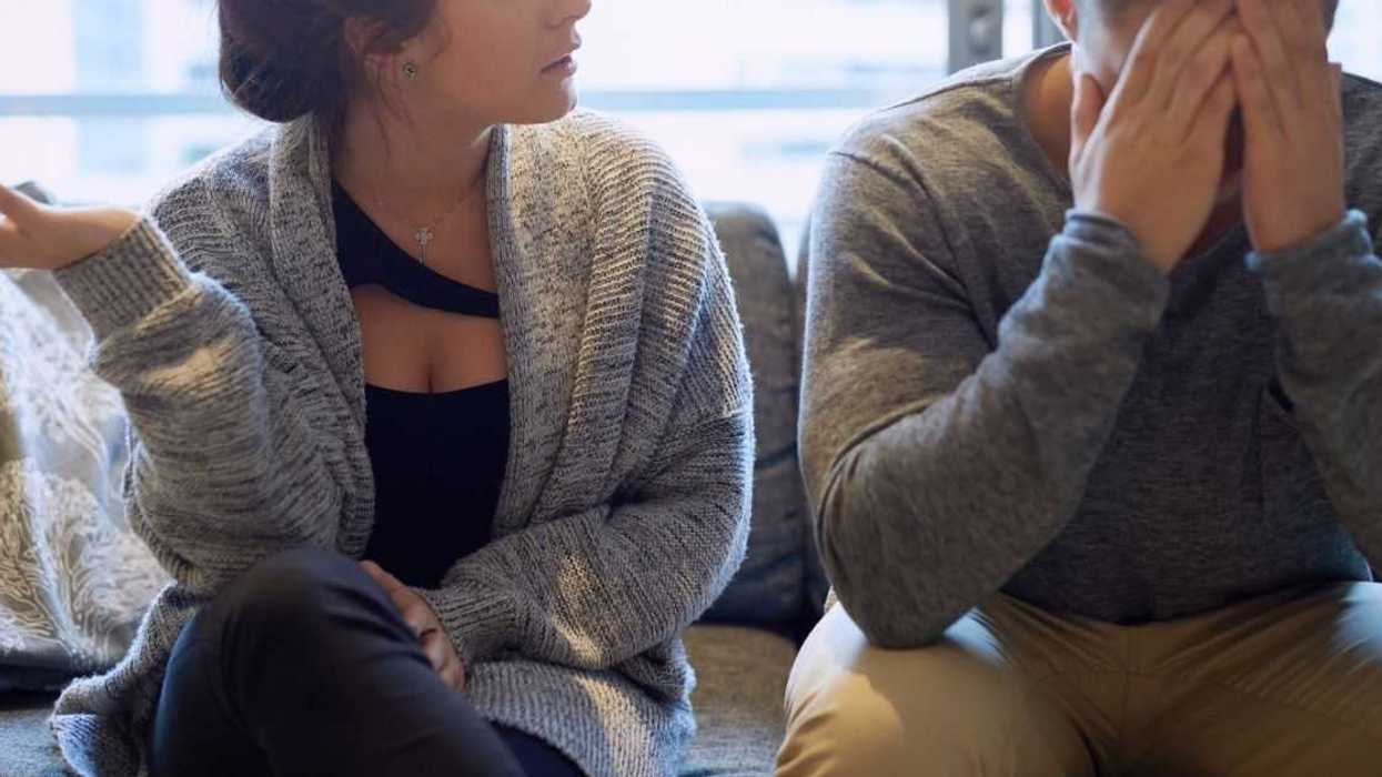 A couple sits on a couch arguing