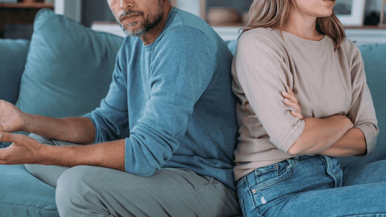 A couple sitting on a sofa facing away from one another.
