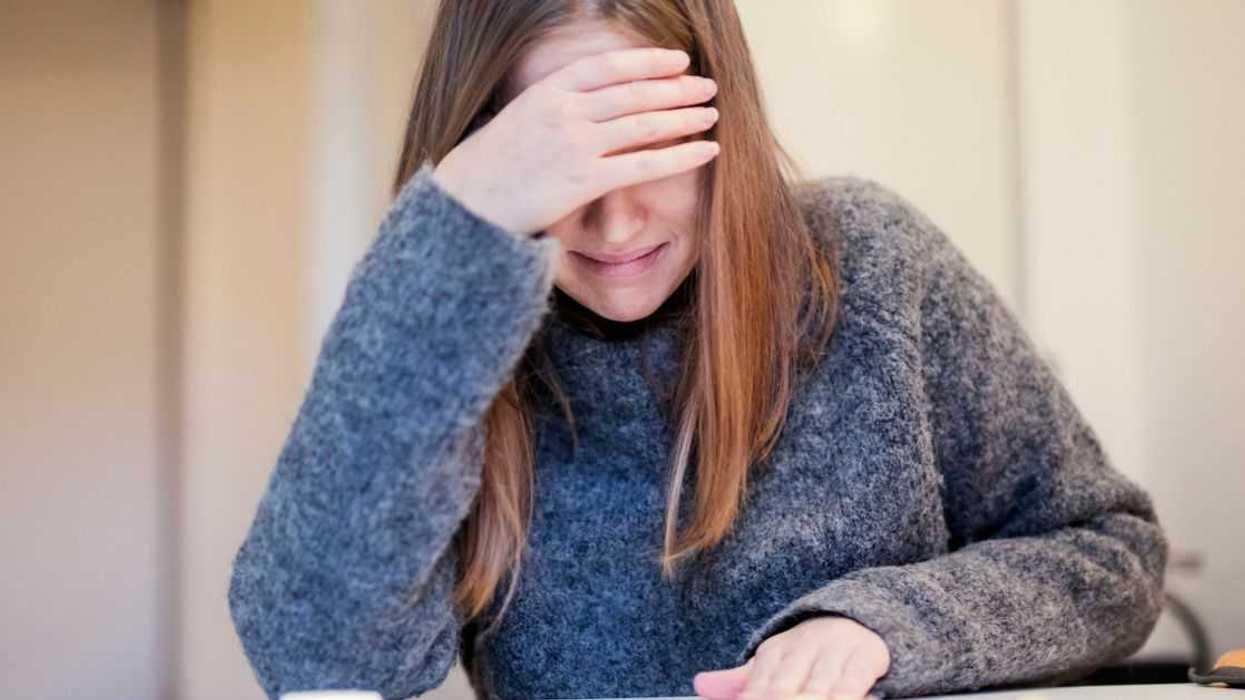 A crying young woman, covers her eyes.