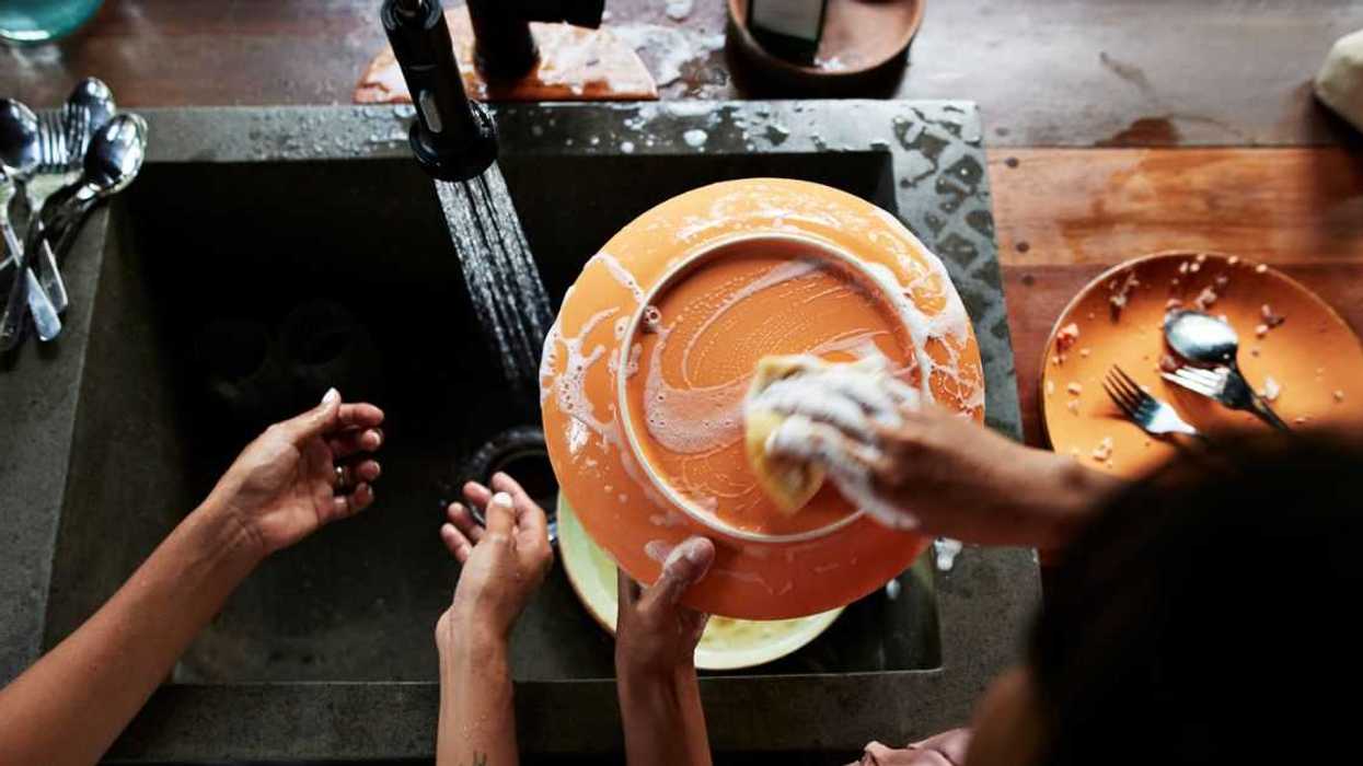 A direct above shot of a mother and daughter washing dishes near sink in kitchen, during vacation.