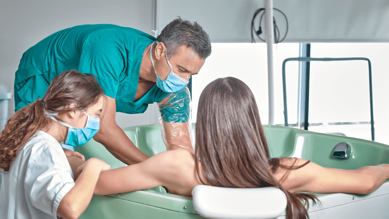 A doctor and a nurse helping a woman in a pool with a water birth.