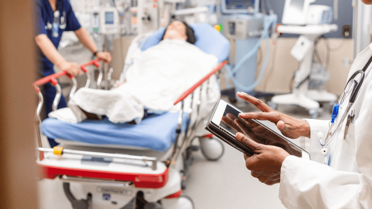 A doctor standing in the foreground of a hospital wing.