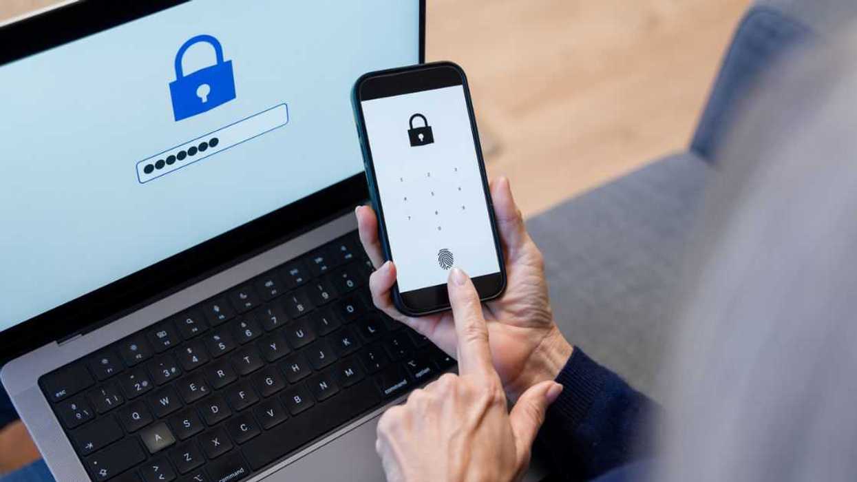 A faceless adult's hands accessing a smartphone and laptop with fingerprint for enhanced security and seamless login experience.