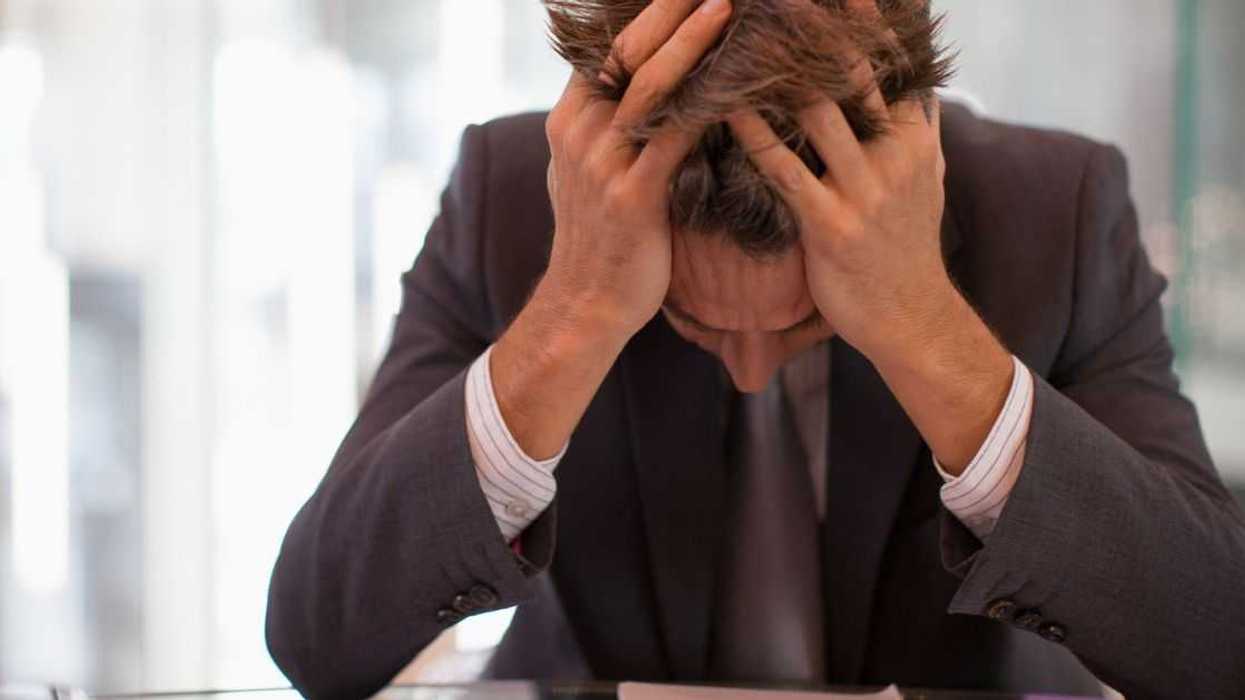 A frustrated man hangs his head in his hands