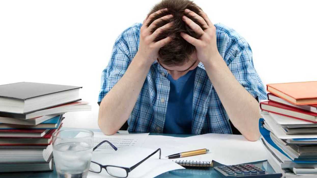 A frustrated student with a lot of homework hangs his head.