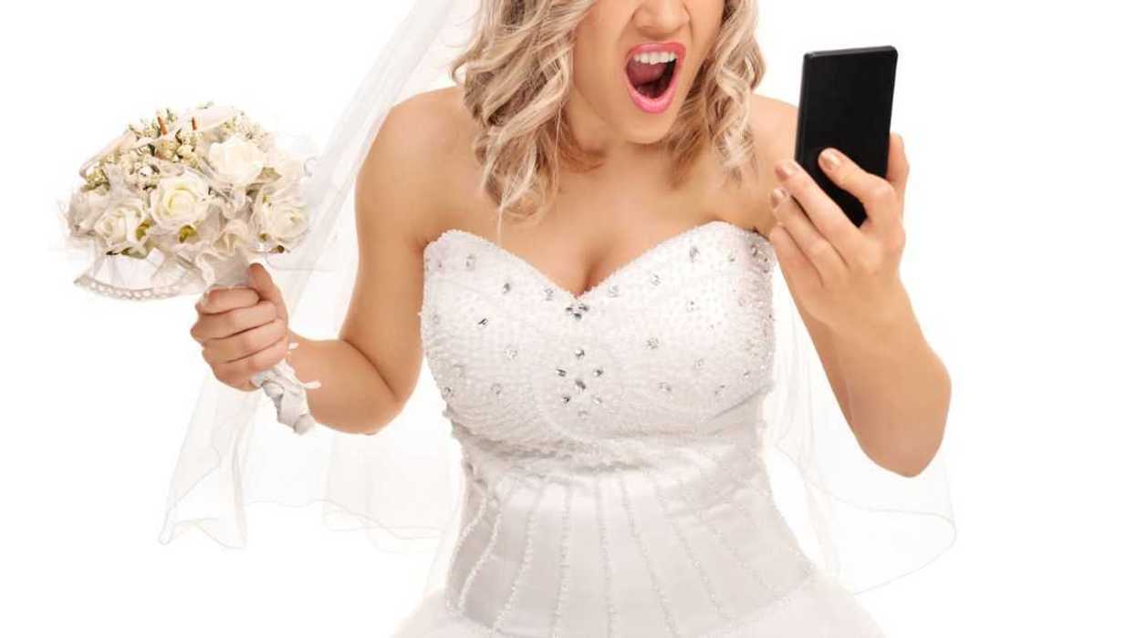 A furious bride looks into a phone while holding a bouquet
