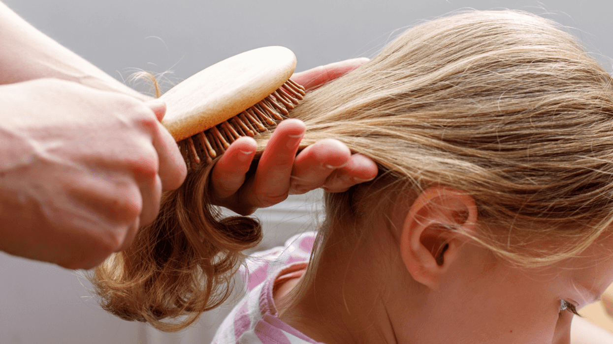 A girl getting her hair brushed.