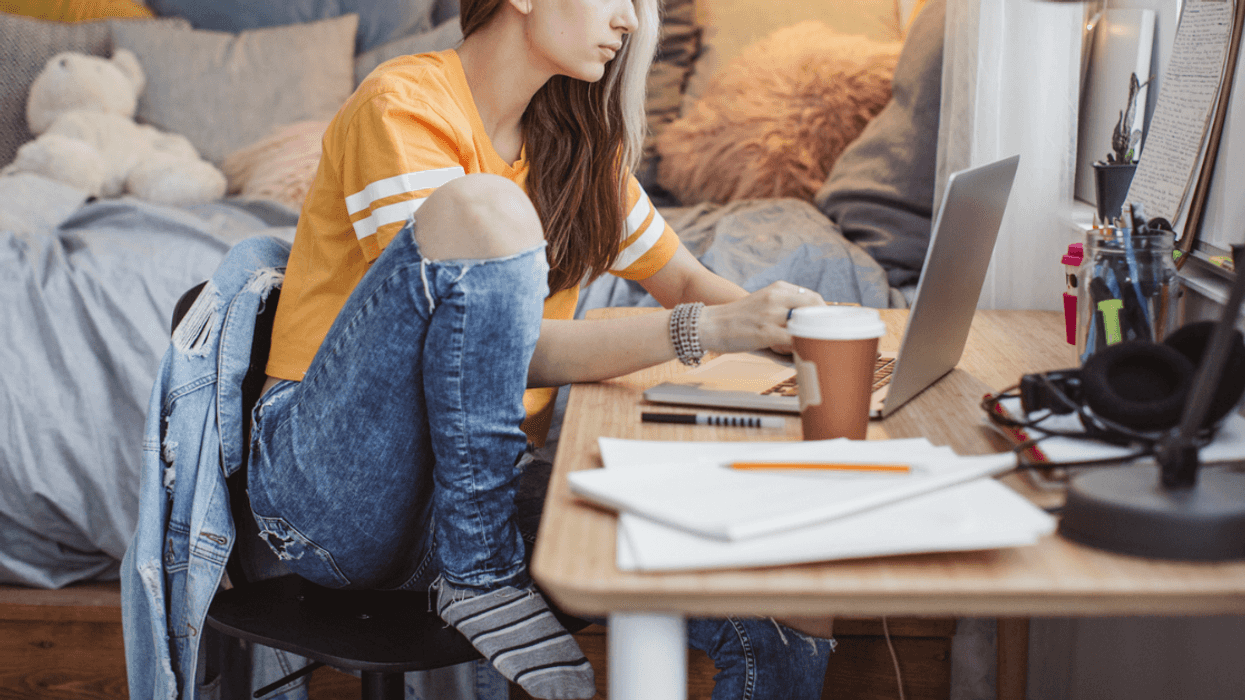 A girl sitting at her desk in a dorm room.