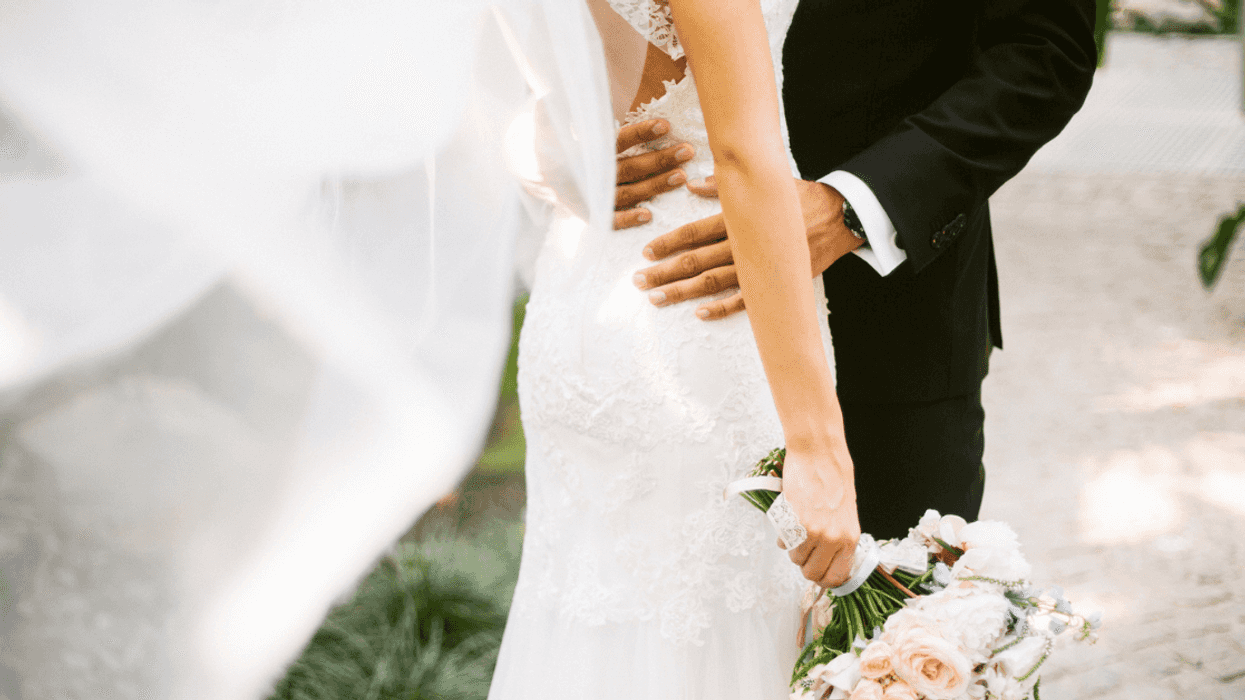 A groom caressing a bride around her waste.