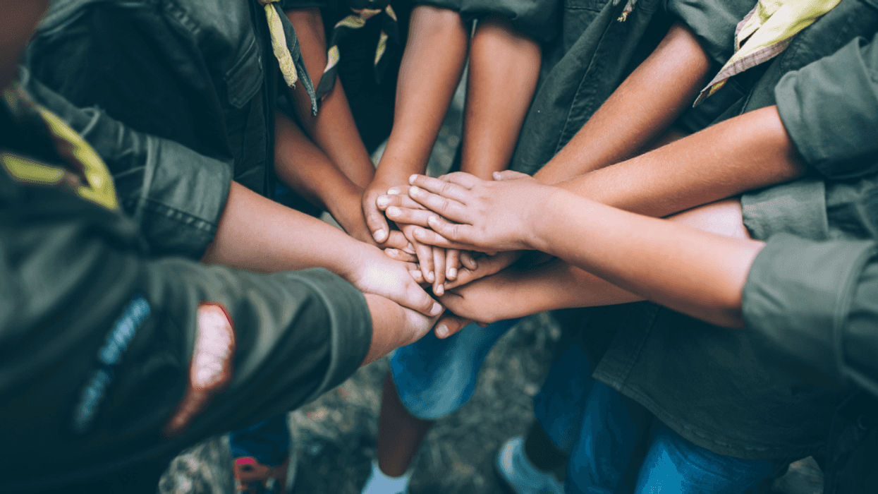 A group of children huddling their hands together.