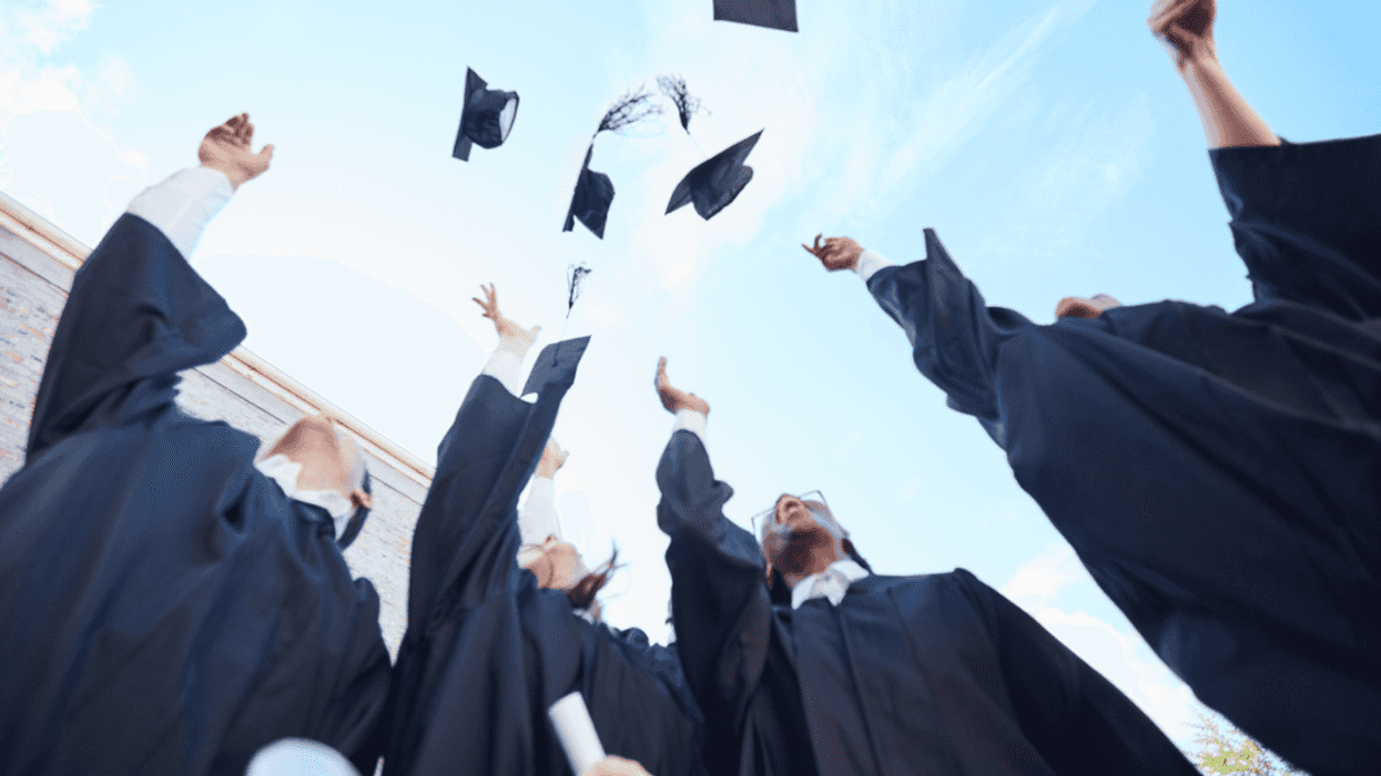 A group of gradating students throwing their graduation caps in the air.