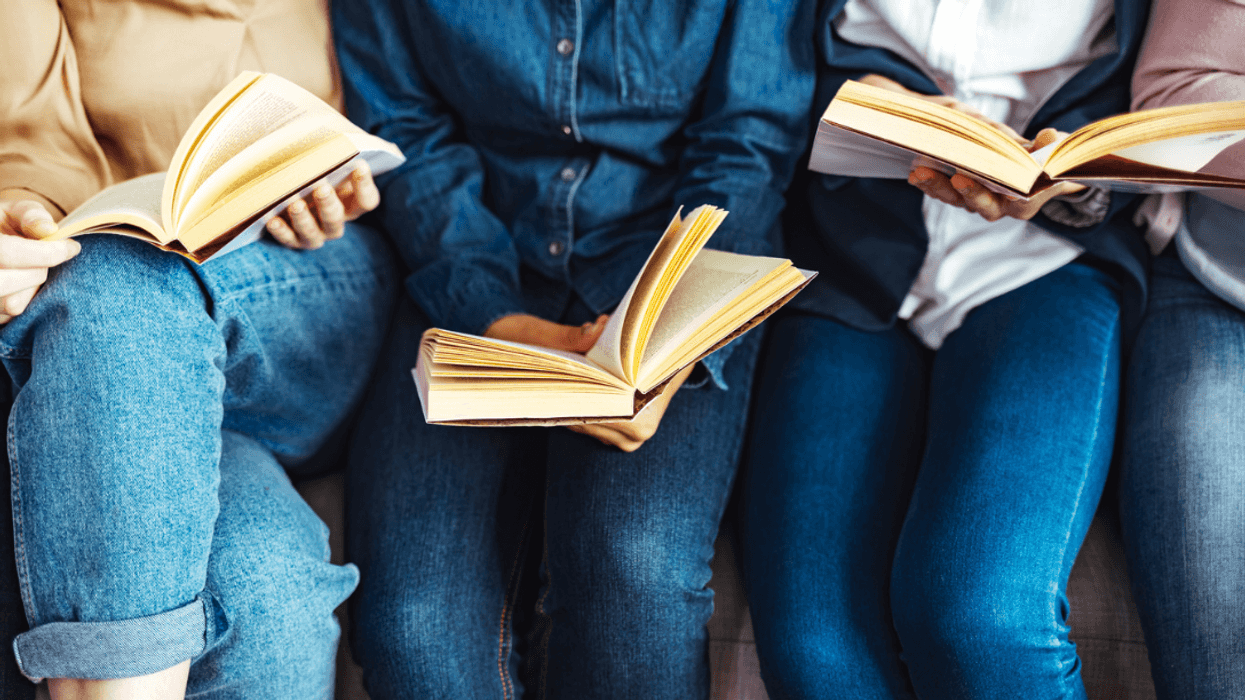 A group of people sitting next to each other reading books.
