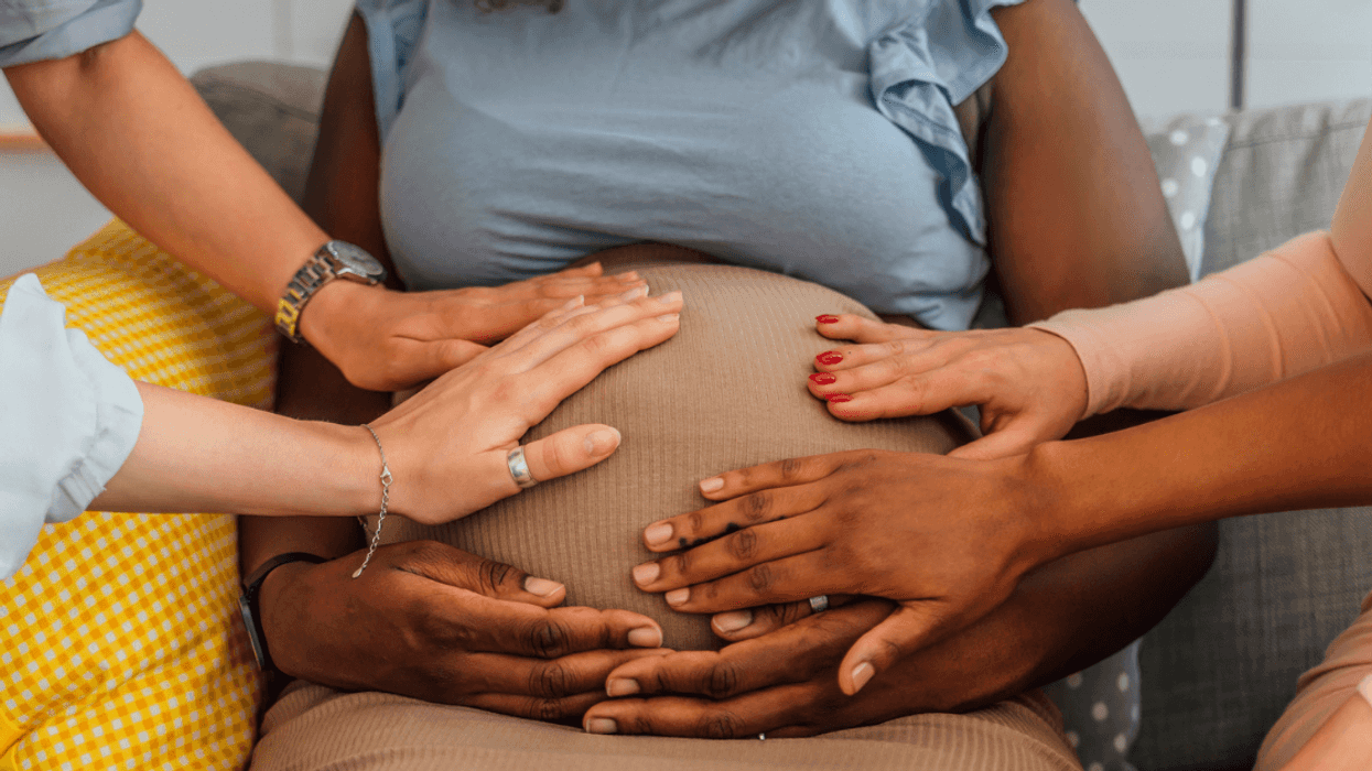 A group of people touching a pregnant woman's stomach.