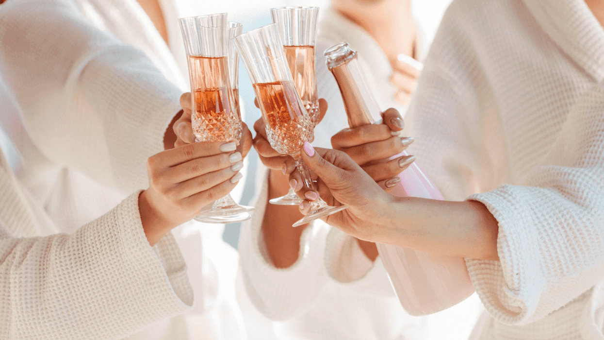 A group of women wearing bathrobes clinking champagne glasses.