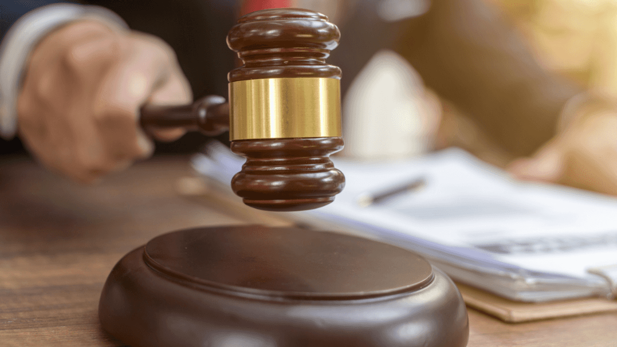 A hand holding a gavel hitting a podium