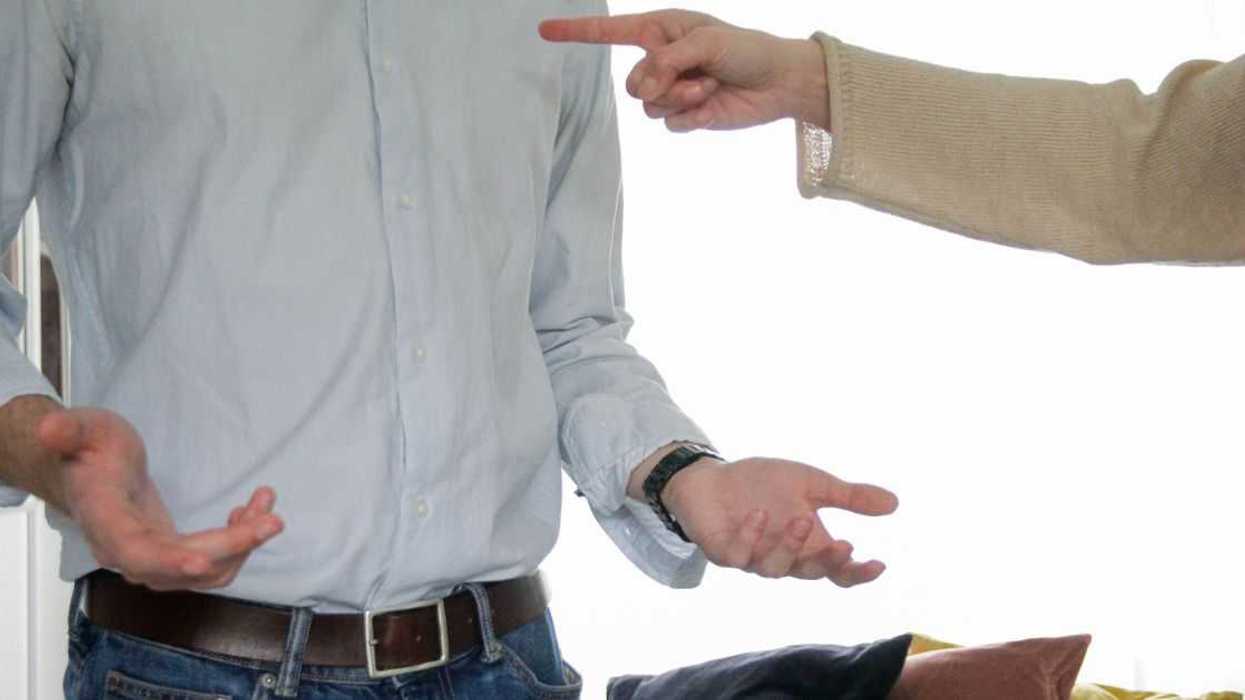 A headless, mid-shot of two men in a heated moment. One man is pointing his finger at the other.