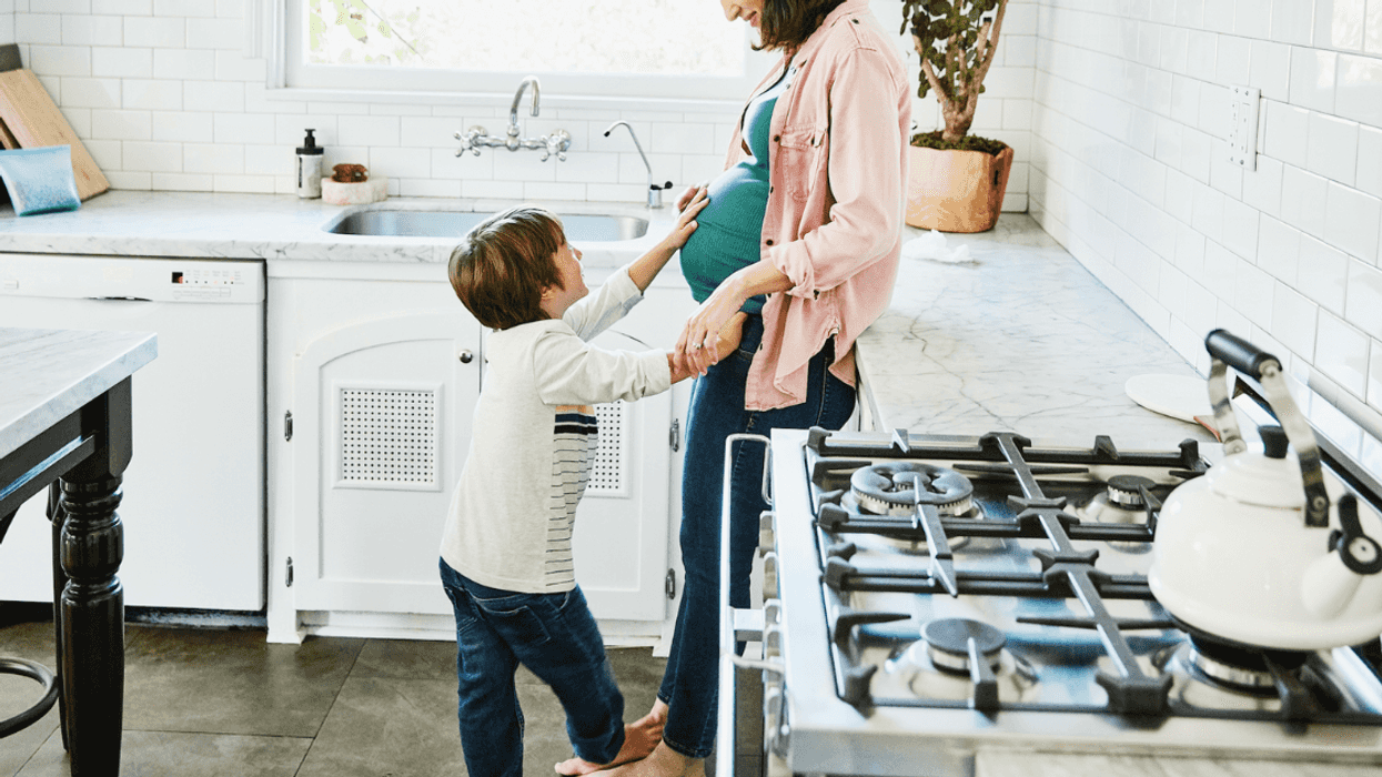A little boy patting the stomach of a pregnant woman.