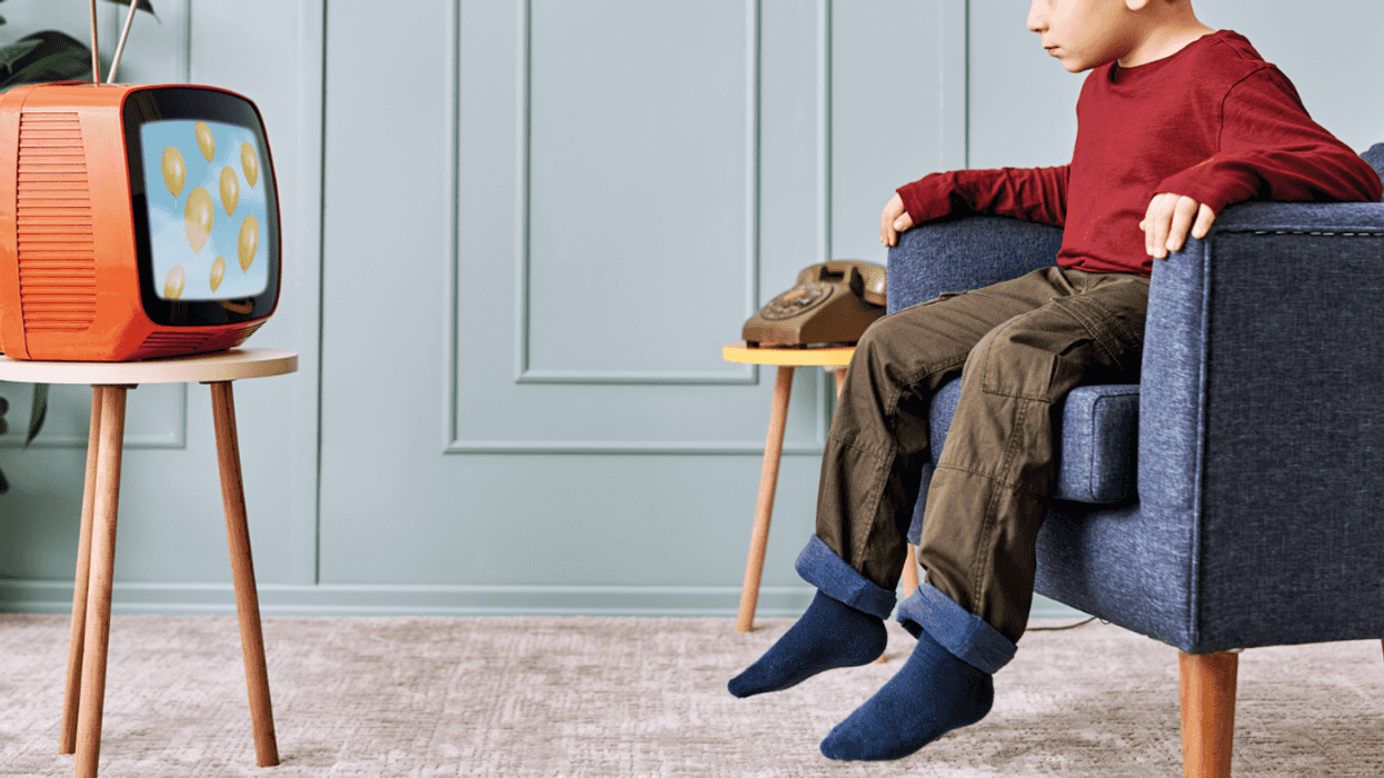 A little boy sitting in a chair and watching television.