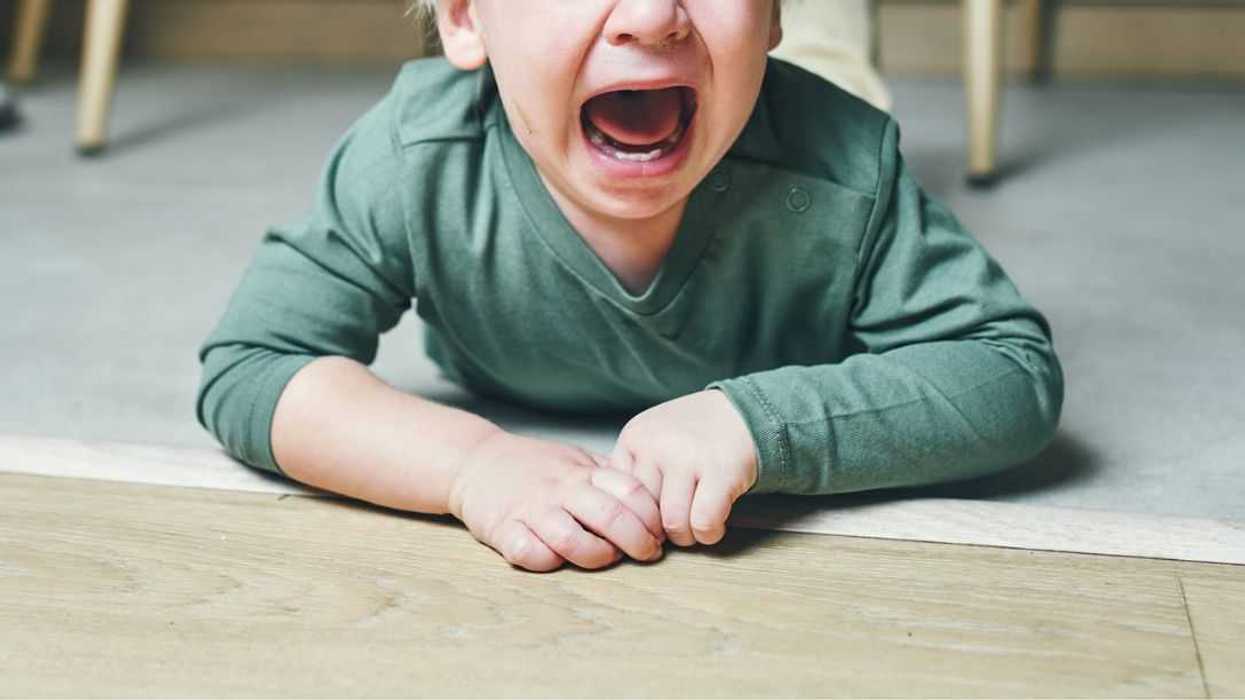 A little boy with blond hair, two years old, is lying on the floor and crying hysterically at home.
