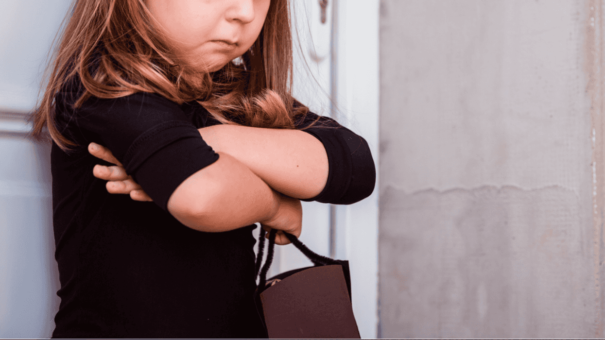 A little girl frowning with her arms crossed.