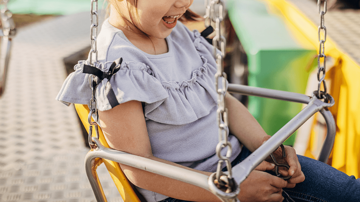 A little girl on a swing ride a an amusement park.