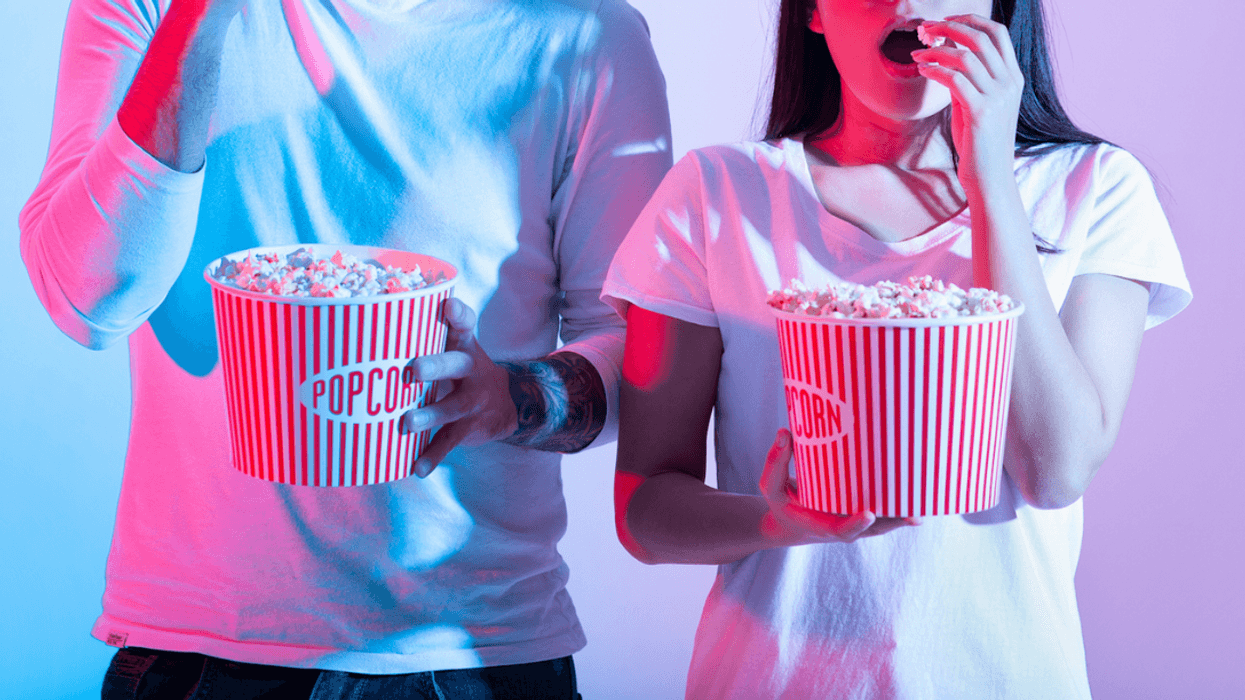 A man and a woman eating popcorn out of buckets