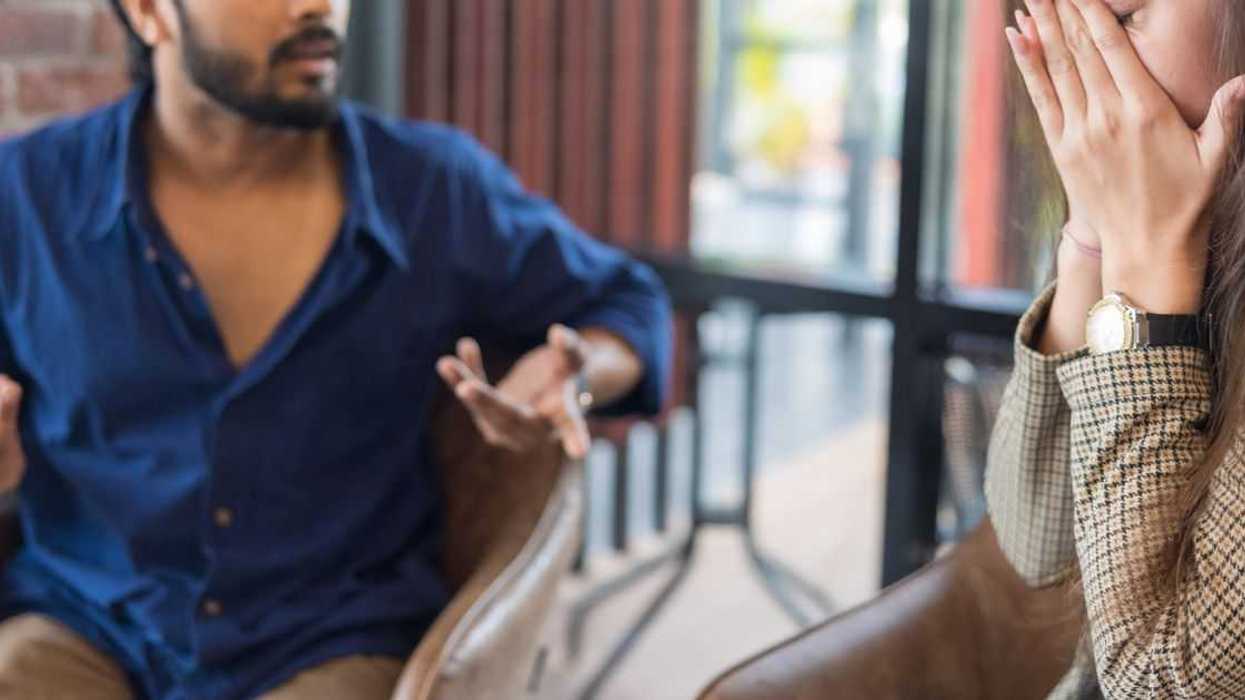 A man and a woman engage in conversation, he seems frustrated, she holds her face in her hands, distressed