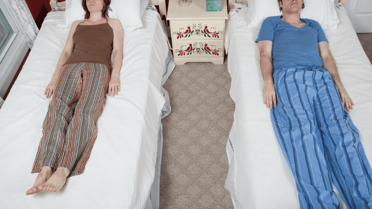 A man and a woman sleeping in twin beds.